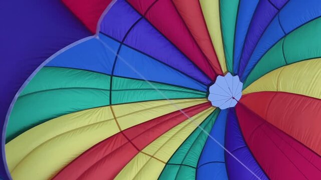 Bright rainbow parasail canopy filling sky over ocean 