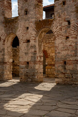 Obraz premium narrow pathways among old stone walls in a historical site. Sunlight casts shadows on the ground, highlighting the textures of the stones