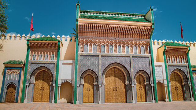 Monumental gate of Fez decorated with zellige tiles, carved arches and golden doors, symbol of traditional Moroccan architecture under a deep blue sky.