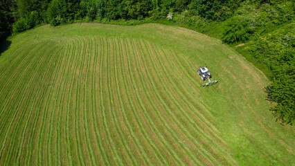 AERIAL: Farm tractor using hay tedder for speed drying of fresh mown green grass © helivideo