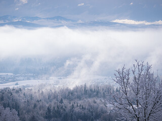 Obraz premium Remains of snowstorm clouds rolling over forested hilly countryside and villages