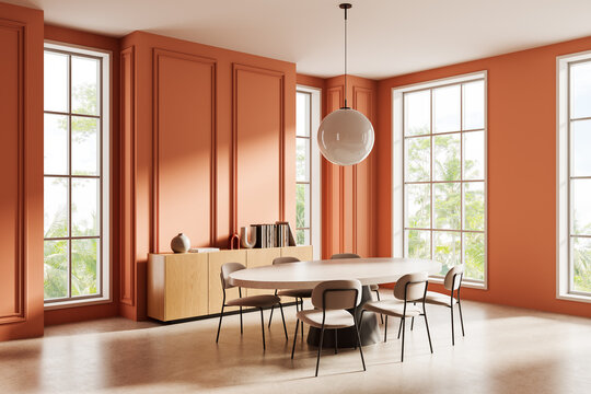 Modern dining room interior with round table, beige chairs, and large windows in a warm terracotta setting, elegant minimal decor and lighting fixture. 3D Rendering