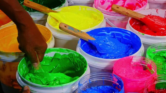 Scoop of Green Plastisol Ink from a White Bottle for Fabric Prints and more, showcasing thick textured paint and wooden spatulas. The image captures creativity artistic expression