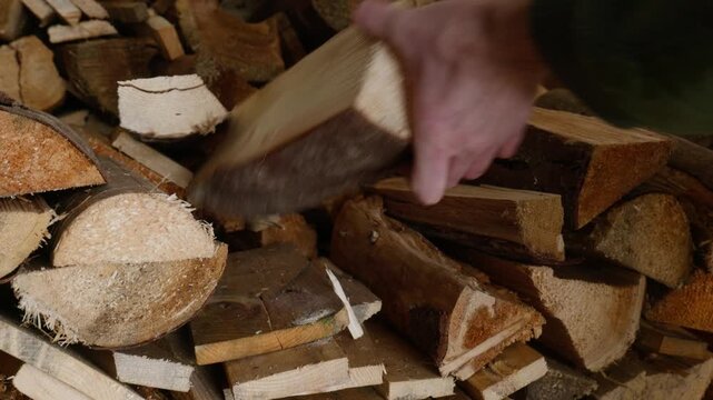 Hands picking up firewood logs from a stack for chopping and home heating preparation