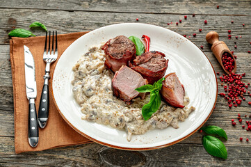 Fototapeta premium Yummy meal with sauce!. The dish features cooked meat served with a creamy sauce and garnished with herbs on a wooden table.
