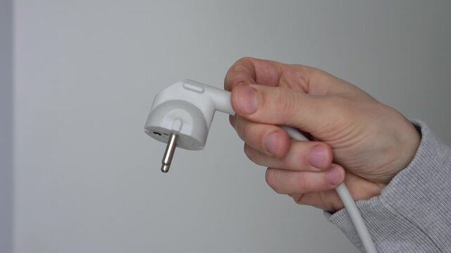 Electrical connector.
An electrical plug and cable in a person's hands.
An electrical outlet for charging electronic devices.