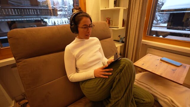 Woman with headphones relaxing and reading an ebook