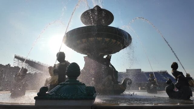 Water spraying from the historic fontaine des fleuves in place de la concorde in paris, france with beautiful backlight from the sun on a clear day creating lens flare
