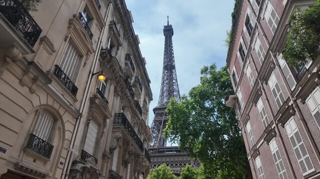 Eiffel tower rising between traditional parisian buildings. Showcasing european city architecture and classic parisian streetscape with landmark structure against a blue sky