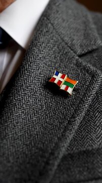 Close up of a tweed suit jacket with a colorful lapel pin