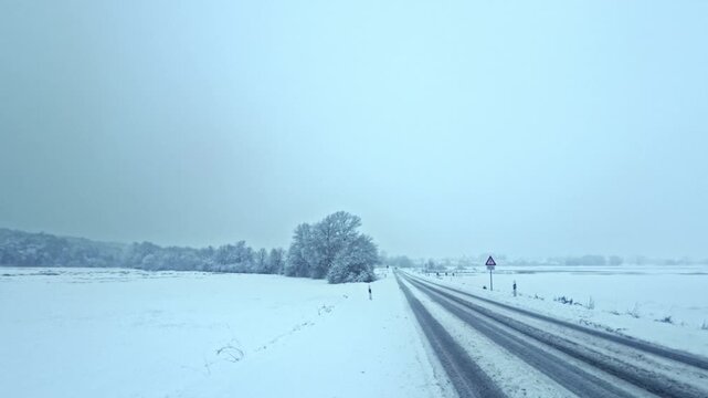 winterliche verschneite Landstra&szlig;e: Auto, Stra&szlig;enverkehr, Glatteis, Schneematsch und eisige Bedingungen, Wintersdienst, Sicherheit, Unfallgefahr, Transport, Landschaft
