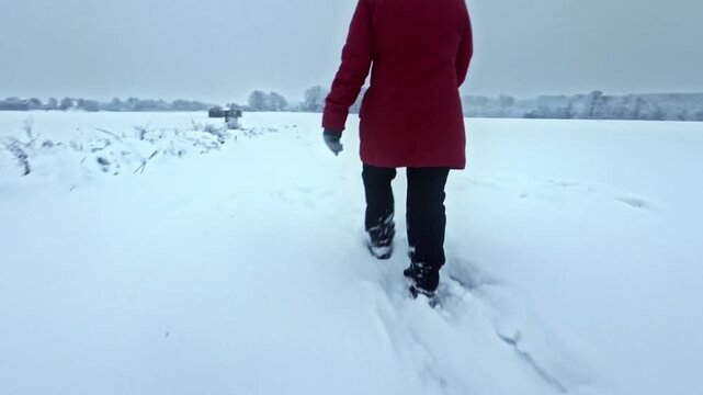 Spaziergang in trister schneeverh&uuml;llter Winterlandschaft: Frau in dicker Jacke stapft durch den Schnee im kalten Winterwetter, Jahreszeit, wandern, frostig, Weite, Ruhe

