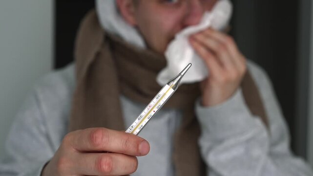 A person with a weak immune system.
A man with the flu.
Symptoms of illness and a high fever.
A man with a cold, wearing a scarf, wipes his nose.