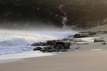 Dawn on the beach, waes breaking at dark rocks and splashing water. Jericoacoara beach, Ceara, Brazil