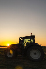 Obraz premium Tractor and agricultural watering pivot irrigation system on a corn field at sunset