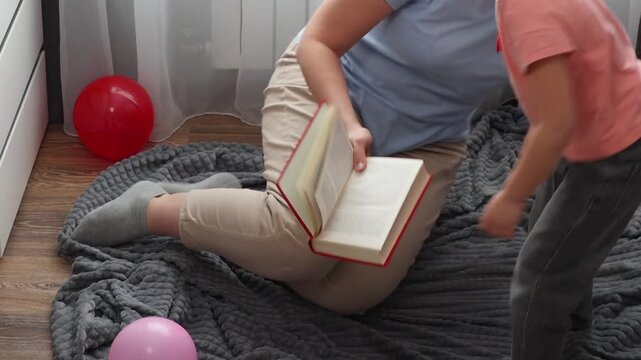 Mother and a Caucasian little daughter are reading a book of fairy tales together. Top view. Concept of Mother's Day and preschool education.