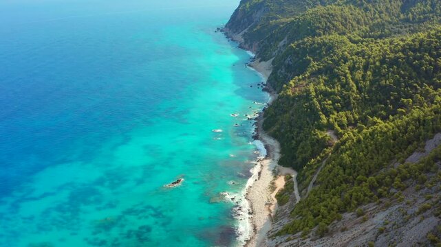 Beautiful coastline in sunrise light on Greek island of Lefkada. Clear water empty beach and bay. Aerial drone overhead tilt