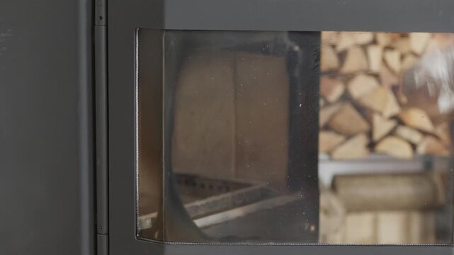 Close up of male hands opening a wood burning fireplace door and starting to clean the dirty glass from soot