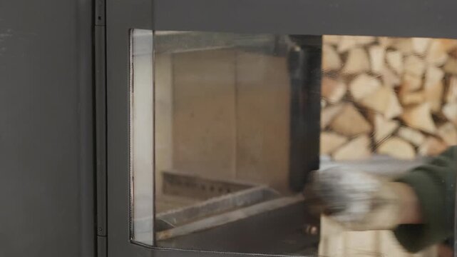 Close up of male hands cleaning dirty glass on a fireplace door with a cloth to remove soot