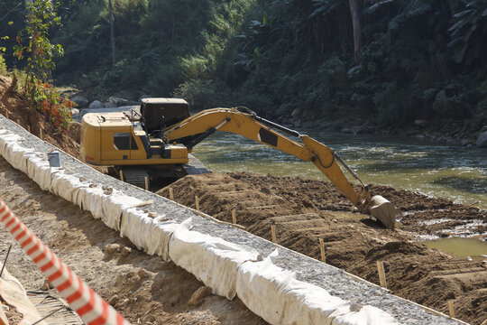 Heavy excavator at construction site doing river bank protection work. An engineering project focused on erosion control and environmental management in natural setting
