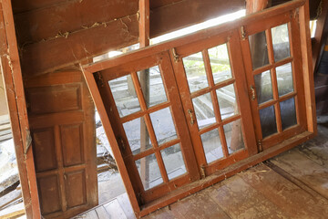 Dusty old wooden window frame leans abandoned in rustic attic. forgotten wood and glass pieces in old house interior create quiet, nostalgic atmosphere