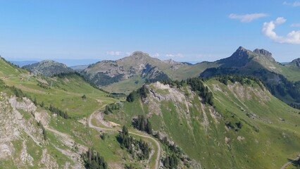 Fototapeta premium French alps expansive summer landscape featuring green slopes, winding hiking trails, and majestic mountain peaks under a clear blue sky, ideal for outdoor activities