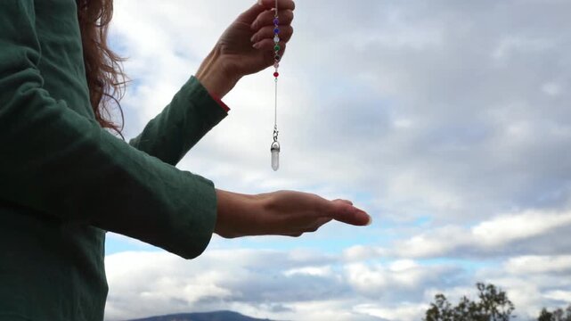 Woman holding a crystal pendulum for divination