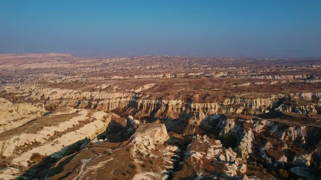 Aerial journey over rugged cappadocia canyon terrain with tuff rocks at golden hour amid vast landscapes.