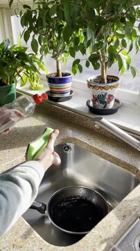 fregando sart&eacute;n y frotando con estropajo esponja en fregadero de cocina restregando con agua y jab&oacute;n