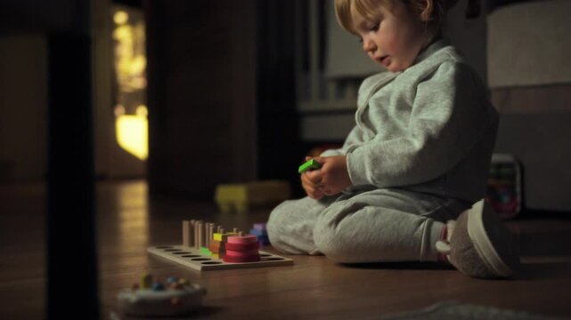 A young girl engages with a vibrant educational game on the floor, surrounded by the warm, cozy glow of evening home lighting, fostering play and cognitive child development