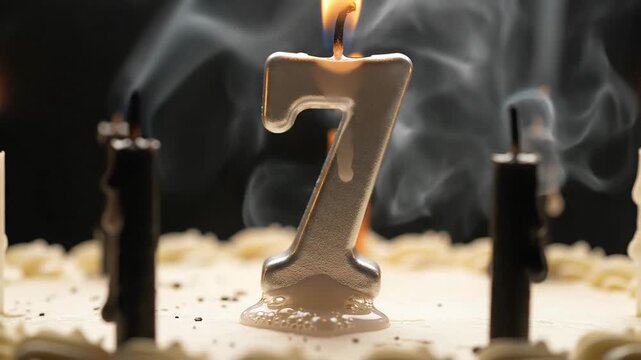 Number 7 Birthday Candle Burning on Cake with Smoke and Other Candles
