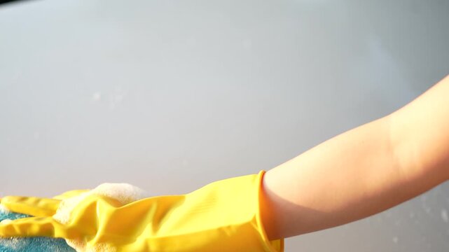 Person Cleaning Surfaces with a Brightly Colored Sponge in a Kitchen Environment with Water Drops and Reflection