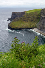 a rainy and stormy summer day at the famous cliffs of moher in the irish County Clare. With a view down to a small beach