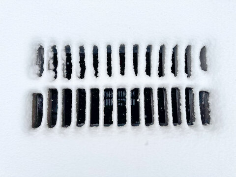 Cast iron drainage grate covered with snow during snowfall
