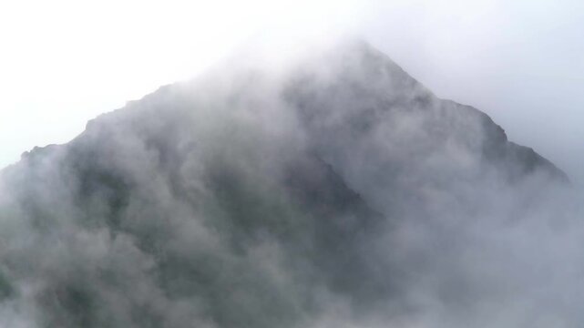 Cinematic time lapse of fog and clouds drifting across cone shaped mountain peak in Ethiopian highlands. Misty atmosphere reveals dramatic volcanic landscape and spiritual African mountain scenery.