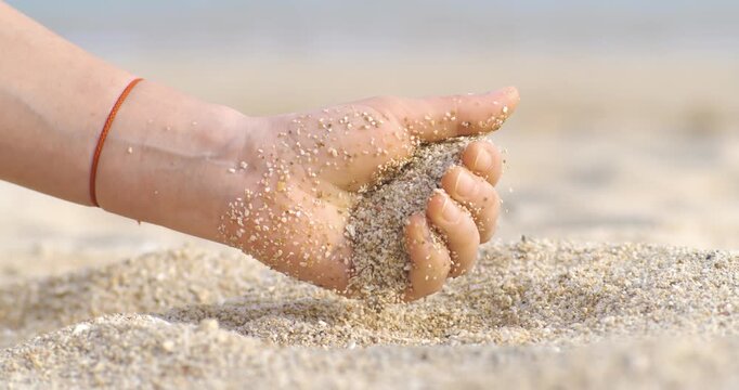 Sand falling from hand in slow motion on a beach. Vacation and travel concept. Shot on super slow motion camera 1000 fps.