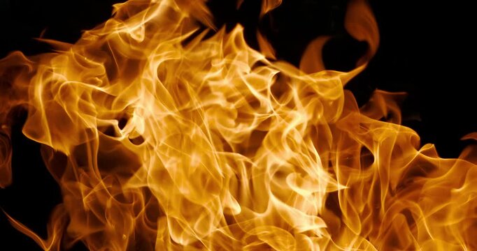 Vibrant close-up of swirling orange fire flames against a dark black backdrop, capturing dynamic heat and motion in abstract fiery texture. Shot on super slow motion camera 1000 fps.