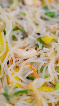 Fresh vegetables with delicate noodles. Colorful rice noodles with crispy vegetables and light dressing. Appetizing closeup of vegetableinfused rice vermicelli with sesame sauce