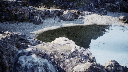Naklejka premium Glistening water reflects the sky while smooth stones frame a peaceful water pool. This serene scene invites moments of reflection at a quiet rocky shore.