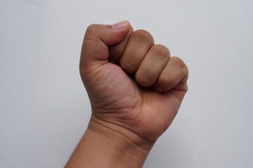 Obraz premium lose-up view of a male hand tightly clenched into a fist against a clean white background. this powerful gesture symbolizes strength. male clenched fist hand gesture isolated on white