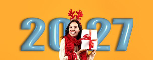Obraz premium A woman wearing festive attire holds a wrapped gift with a bow. She stands before large numbers representing the upcoming year. The background is bright and vibrant.