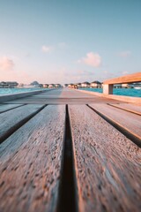 Fototapeta premium Wooden pier reaching overwater bungalows in maldives at sunset