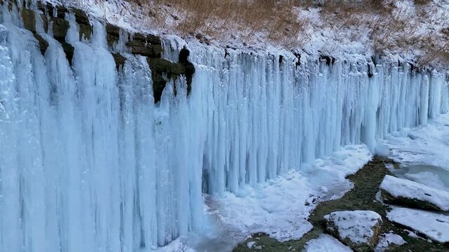 4K drone footage of a blue ice wall formed by a frozen waterfall inside a deep canyon. Tamshaly Canyon, Mangystau, Kazakhstan. Winter nature landscape, ice formations, cliffs, wild environment, aerial