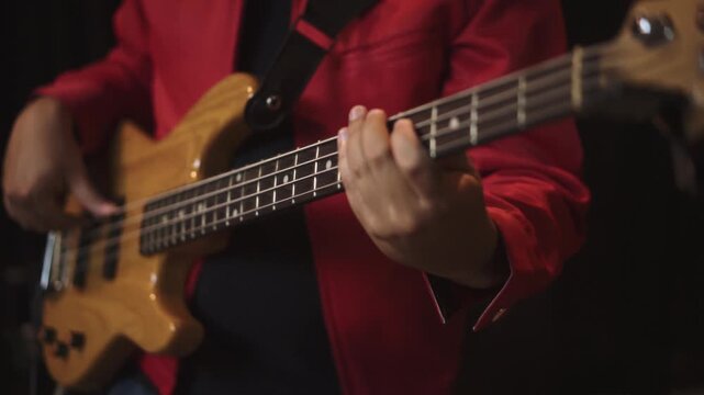 Close-up of bassist playing electric bass guitar in music studio