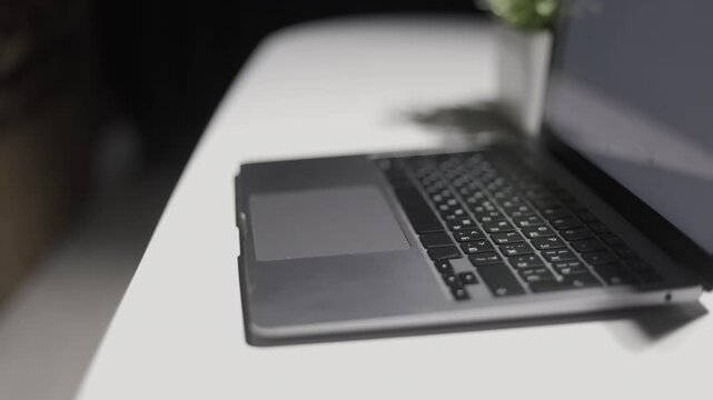Close-up of a modern laptop keyboard and trackpad on a white surface with soft lighting
