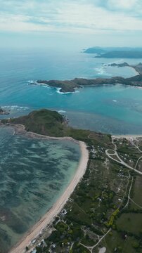 Aerial Coastal Village And Coral Flats,Long Sandy Ribbon Curving Along Shallow Turquoise Shelf, Scattered Houses And Vegetation,Reef Patterns Visible Through Clear Water, Katil beach,Lombok,Indonesia