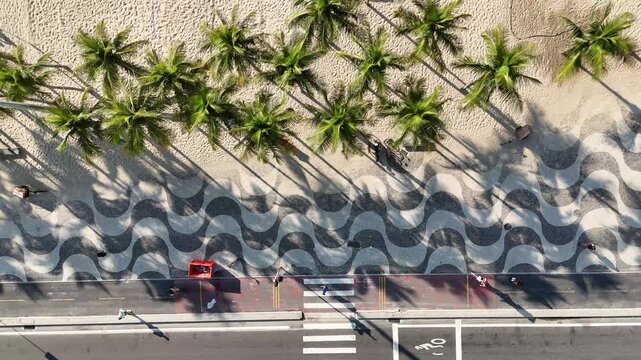 Morning drone shot of people jogging on Copacabana sidewalk, Rio de Janeiro