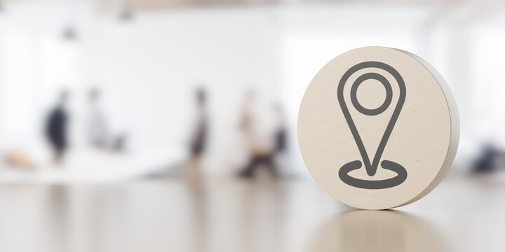 Location marker icon on round standing wooden puck on table with office background, contact or adress business concept with copy space