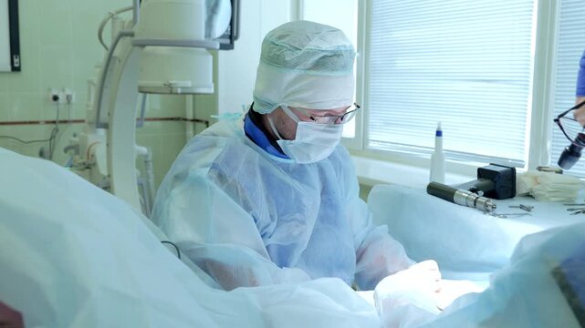 Russia Tomsk 05.07.2025: Medical procedure scene, Doctor performing hand surgery silently, Surgeon clothed in sterile gear operating attentively, Health professional conducting precise hand