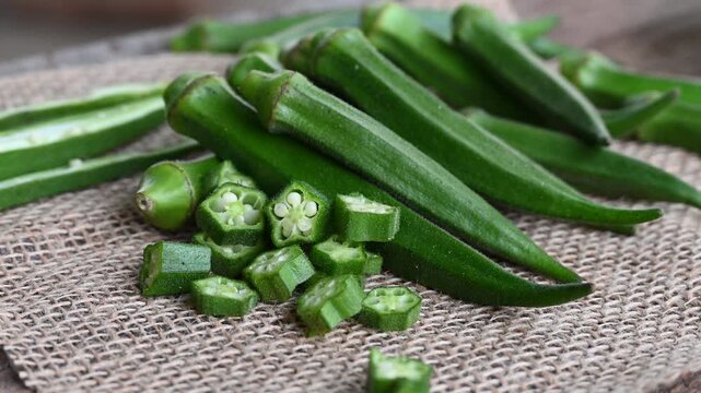 Farm fresh raw okra slices on wooden rustic aged chopping board. Close up of Lady Fingers or Okra over wooden background.